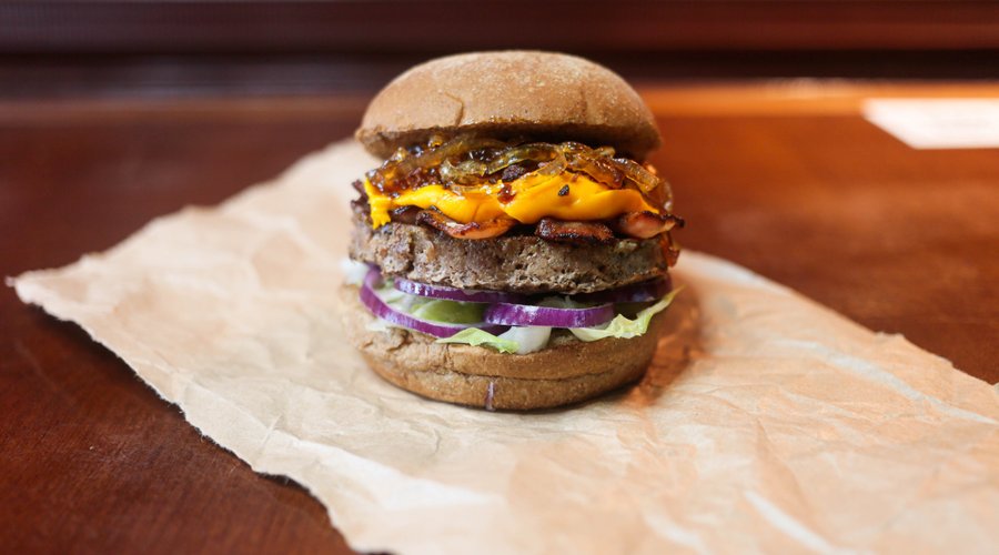 Hambúrguer artesanal de carne Blend da casa 150gr , alface americana, cebola roxa, cheddar, muito bacon, cebola caramelizada e farofa de bacon no pão Australiano ou no pão sem glúten. Acompanha batata chips, maionese verde da casa e maionese picante artesanal.