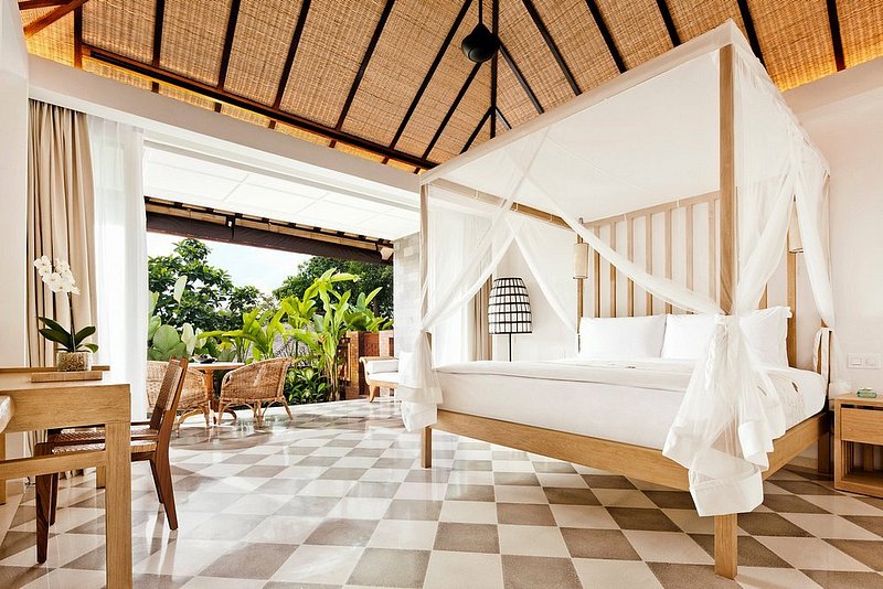 Una habitación de hotel en COMO Uma Ubud, Bali, con una cama con dosel y mucha luz natural