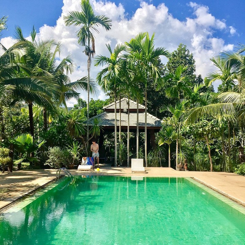 Un hombre preparándose para nadar en la gran piscina color turquesa de Mae Nai Gardens, un hotel en la jungla en la campiña de Chiang Mai