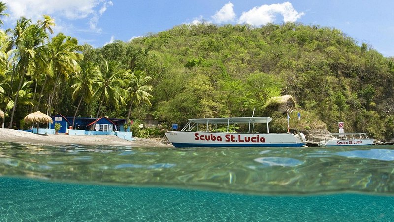 Boat with "Scuba St. Lucia" written on it, in water next to shore