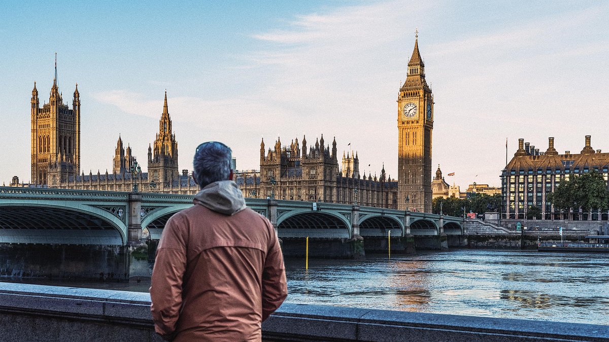 A man looks at Big Ben and Westminster Bridge in London at sunrise