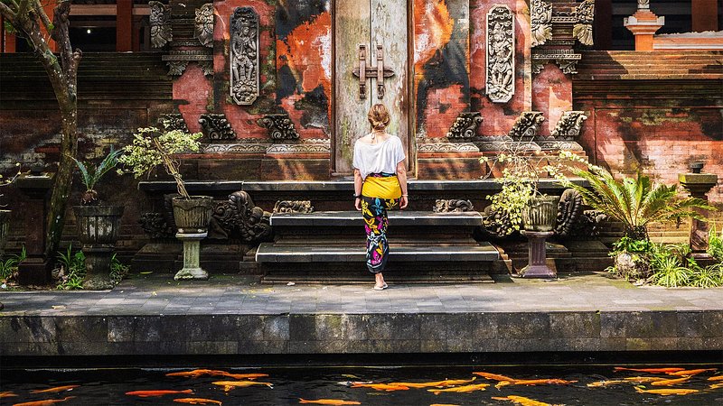 A woman walks up the steps to the front gates of a Balinese temple