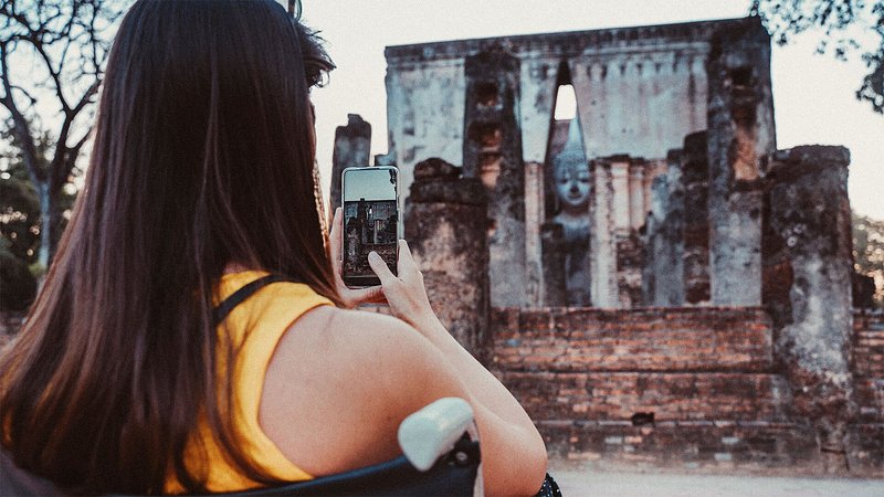 Woman photographing ancient ruins with cell phone 