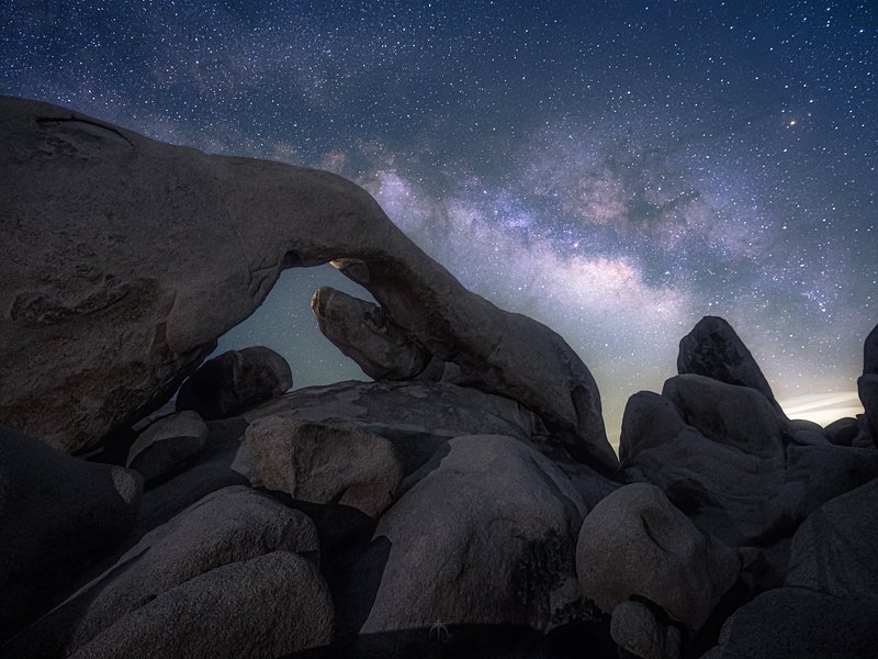 A view of the milky way above the iconic Arch Rock in Joshua Tree National Park, California.