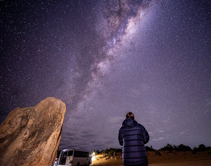 Een man die naar de sterren boven The Pinnacles Desert kijkt, Cervantes, Australië.