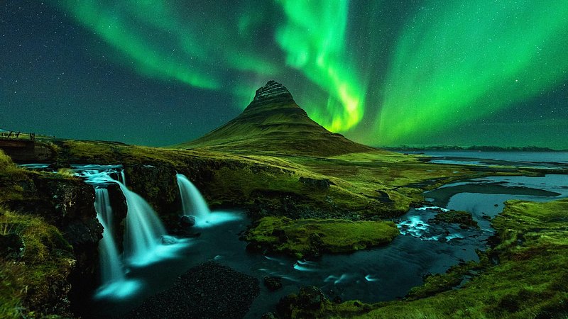 Northern lights over Mount Kirkjufell and Kirkjufellfoss waterfall in Iceland 