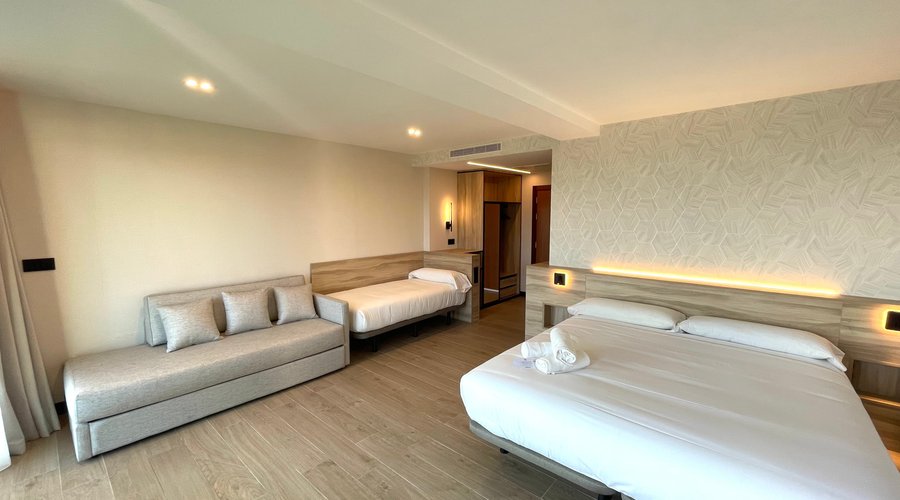 HABITACIÓN TRIPLE PREMIUM Habitación de 36m2 + terraza de 5m2 - Vistas al mar. Habitación totalmente reformada y climatizada. Dispone de dos grandes ventanales, para disfrutar de unas impresionantes vistas al mar. Dormitorio con cama KING-SIZE, o dos camas individuales, una cama extra de 90 y un sofá. Baño con ducha de 120x120 RAINSENSE, aire acondicionado, espejo de aumento, secador de pelo, amenities ecológicos Smart TV 50”, nevera, teléfono, caja fuerte, mobiliario exterior, wi-fi gratis.