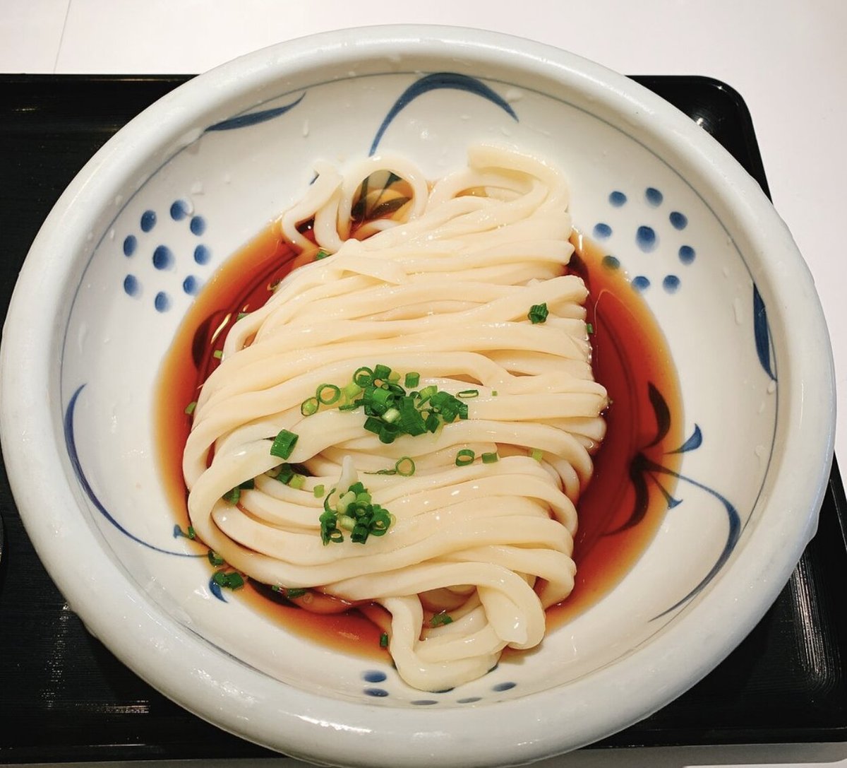 A china bowl with noodles in sauce.