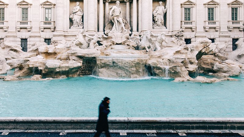 A man silhouette walking next to Trevi Fountain in Rome