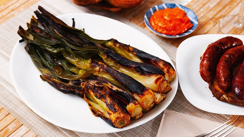 Roasted calcotada, served on a table with romesco sauce and botifarra