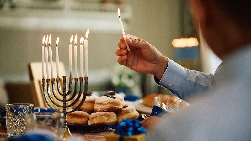 Close up of man lighting candles in menorah while celebrating Hanukkah