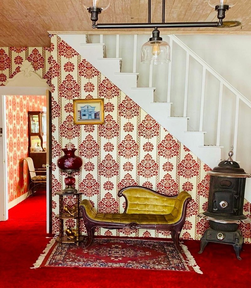 Mustard-yellow velvet seat atop red carpet next to staircase