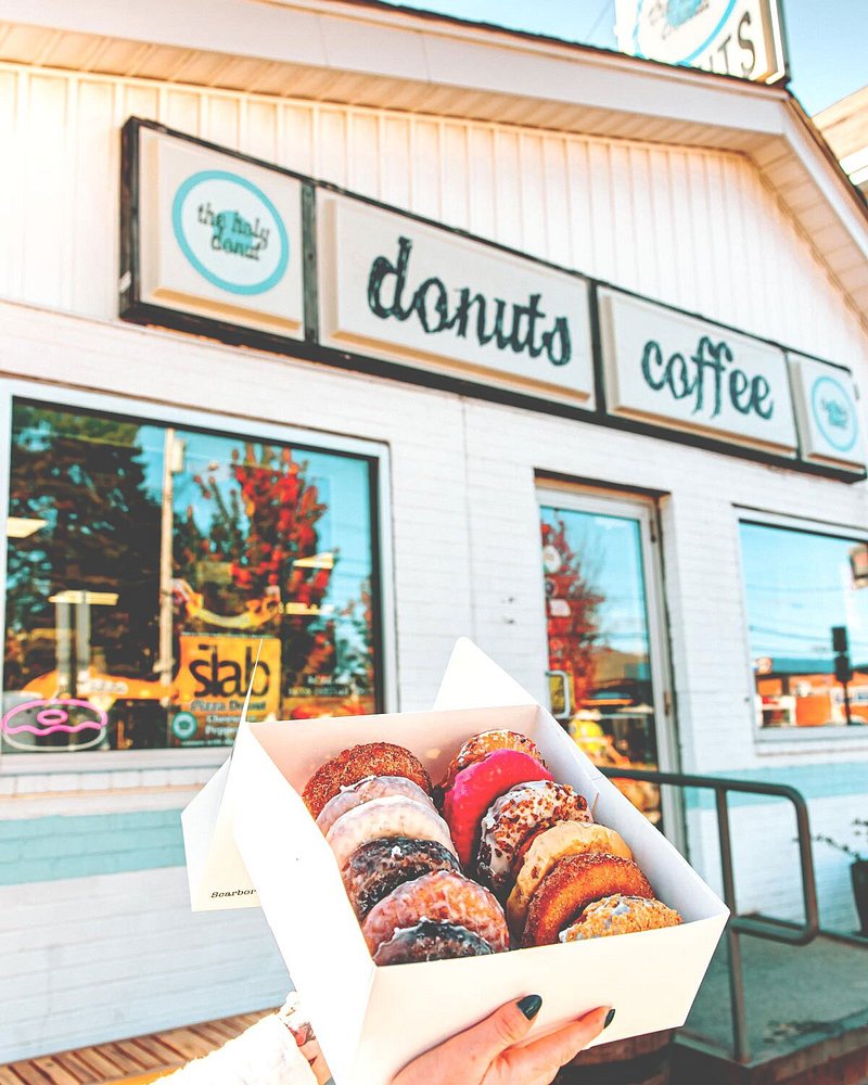 Box of 12 doughnuts being held up in front of shop