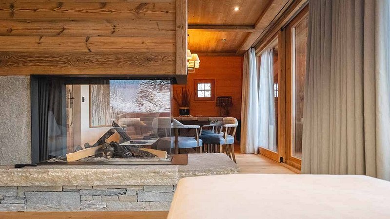 Interior of a spacious chalet at L’Alpaga Hotel, featuring a fireplace and cozy dining area