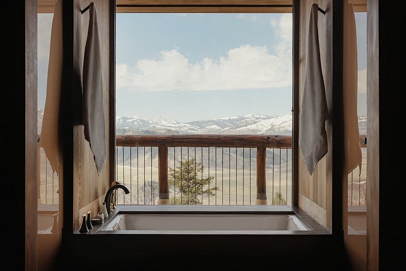 A bathroom with a deep-soaking tub in Amangani, with views of snow-capped mountains in the background