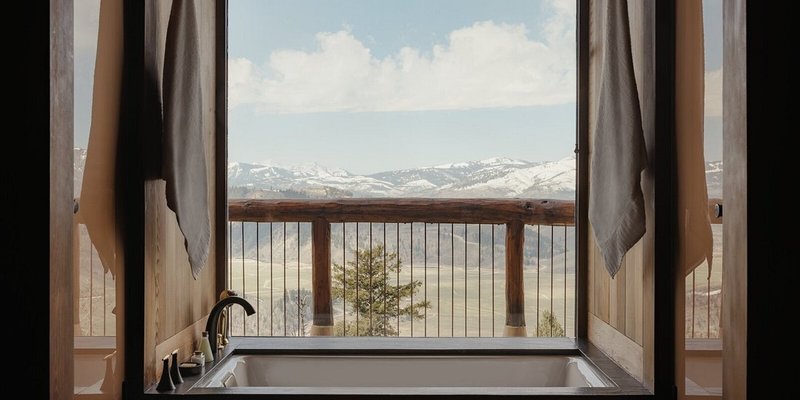 A bathroom with a deep-soaking tub in Amangani, with views of snow-capped mountains in the background.