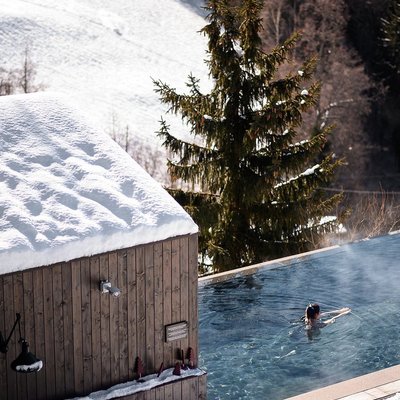A female traveler swimming in the heated outdoor pool at Miramonti Boutique Hotel.