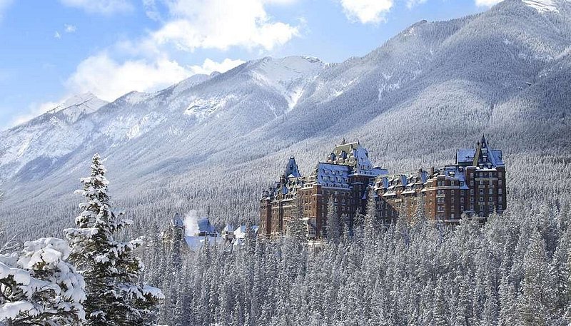 Exterior of Fairmont Banff Springs, a hotel resembling a castle, in the middle of a snowy forest