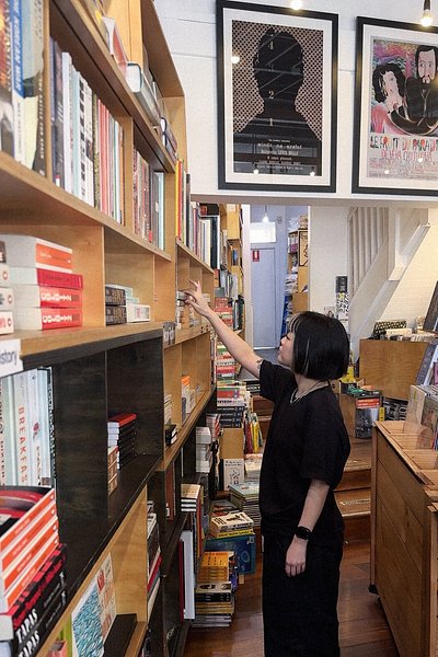 A woman browsing from a shelf of books at TITLE Store