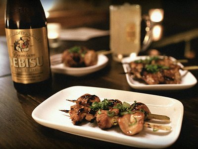 A table with a beer and plates of yakitori skewers at Tokyo Bird