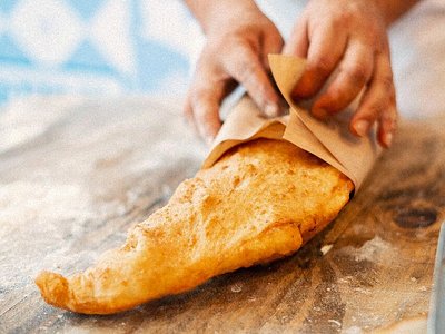A person wrapping a pizza fritta at Pizza Fritta 180