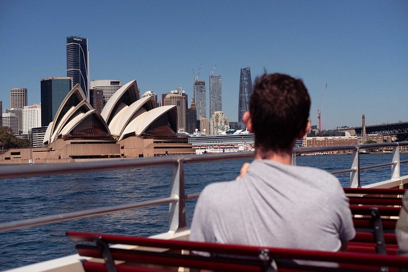 A man sitting on the Sydney ferry looking out towards the Sydney Opera House