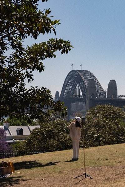 A woman standing on Observatory Hill and admiring the Sydney Harbour Bridge