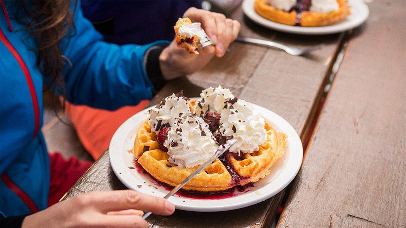 Skiers eating Belgian waffles with chocolate and whipped cream