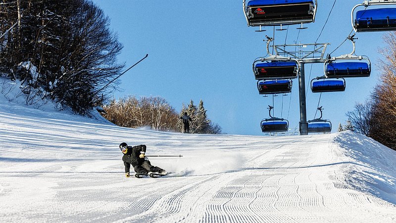 Person skiing down run next to ski lift at Killington