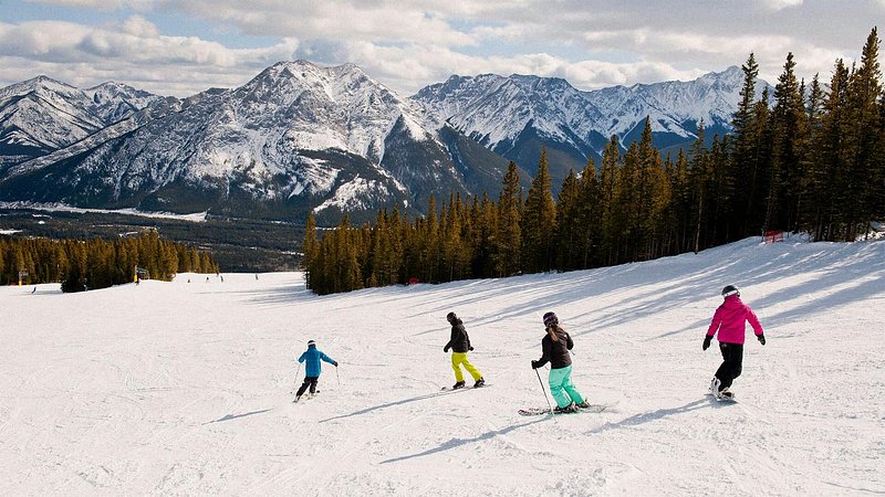 A group of skiers go down a snow covered trail in Canmore, Alberta