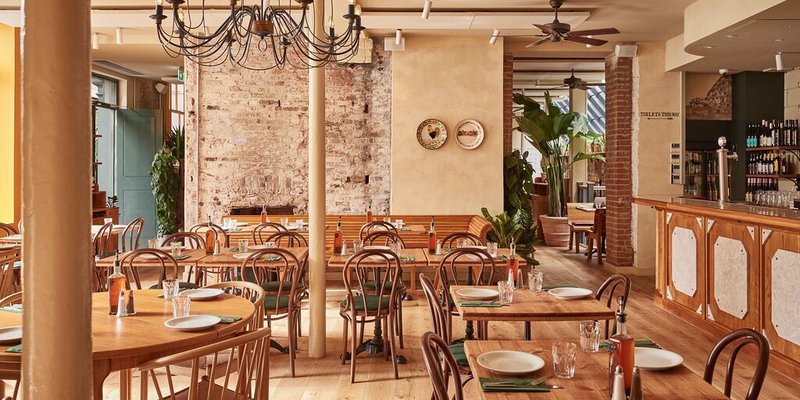 Restaurant interior with wood floors, dining tables, and bar area