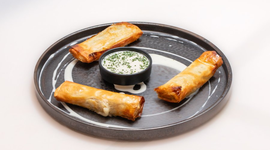 Croccante. Croccanti involtini cotti al forno ripieni di verdure a foglia larga, guanciale e provola, serviti con una fonduta di Parmigiano Reggiano 