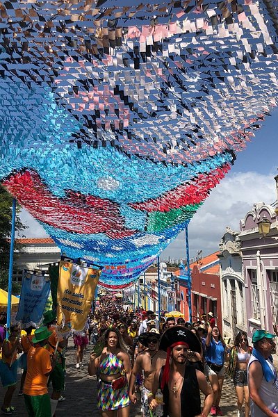 브라질의 올린다 카니발에서 파티를 즐기는 많은 인파 위로 형형색색의 종이 깃발이 매달려 있는 모습