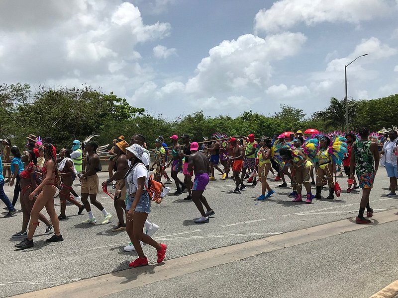 그랜드 카두멘트 데이에 크롭 오버 페스티벌에서 화려한 의상을 입고 길을 걷고 있는 바베이도스 사람들