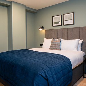 Accessible Apartment - Bedroom with side table, open wardrobe and luxurious blue quilt