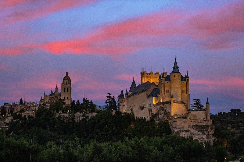 黃昏時分的塞哥維亞城堡，粉紅色和紫色交織的晚霞在湛藍的天空中綻放光彩。