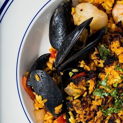 Seafood paella on white plate with blue trim