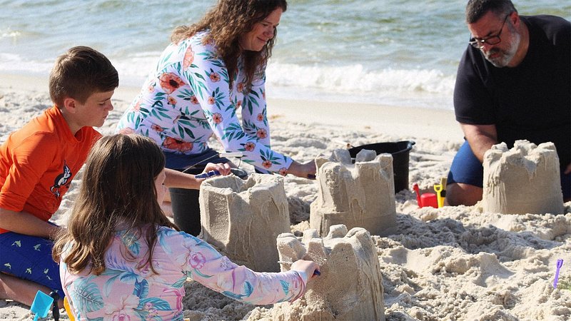 Family building sand castles on the beach in Gulf Shores, Alabama