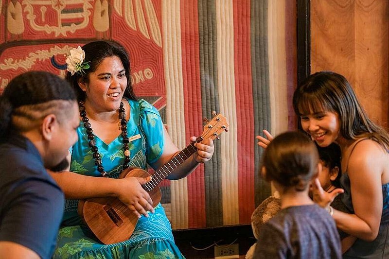 Women in a blue dress playing a ukulele. 