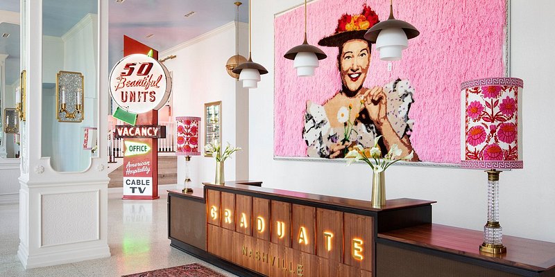 A pink-and-red painting above a credenza decorated with neon at the Graduate Nashville.