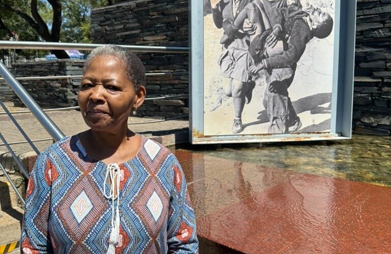 This is Hector Pieterson's sister. In the background you can see the famous picture of the photograph of her brother being carried. 