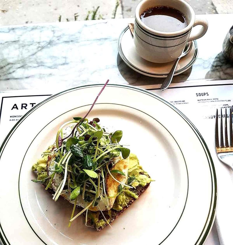 Avocado toast with fried egg next to mug of coffee