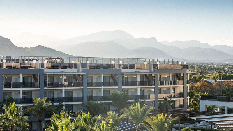 An exterior of a building surrounded by palm trees and mountains.