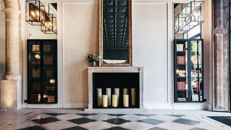 A marble checkerboard floor and a fireplace set with candles.