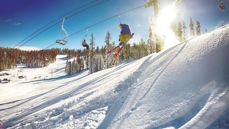 Skiers on chairlift over snowy mountain