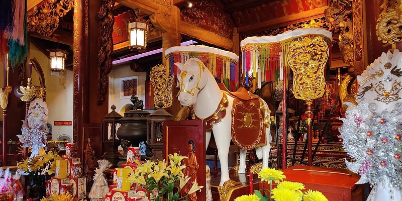 Opulent, colorful interior of temple with horse sculpture, gold, and flowers