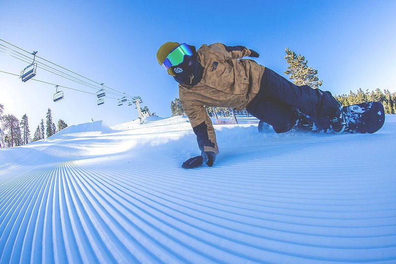 Person snowboarding with one hand on snow, plus chairlift in background