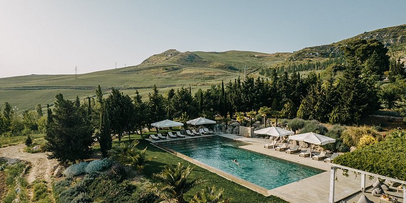 A swimming pool surrounded by lush hillsides and evergreen trees.