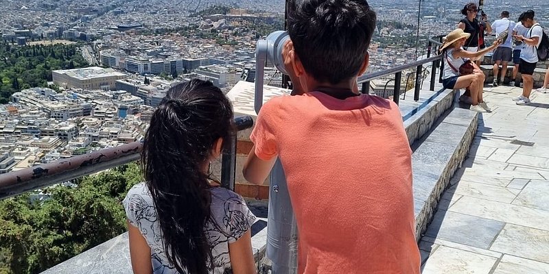 Two kids looking through the view-finder at the top of Lycabettus Hill.