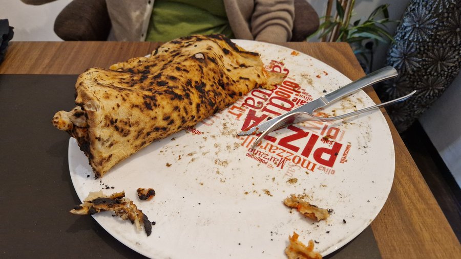 Die Pizza ist gefaltet, um die Unterseite der verbrannten Pizza zu sehen
